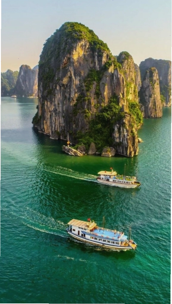 Du thuyền nhỏ giữa vịnh biển xanh và núi đá