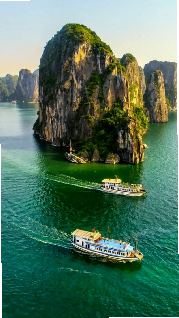 Du thuyền nhỏ giữa vịnh biển xanh và núi đá là một bức ảnh phong cảnh đẹp