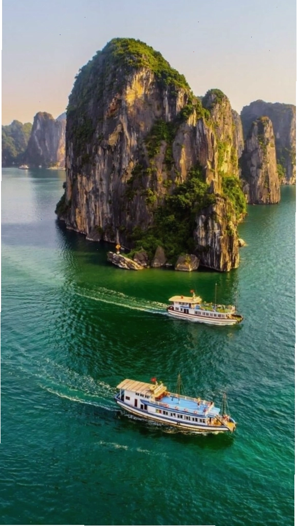 Hình nền du thuyền nhỏ giữa vịnh biển xanh và núi đá