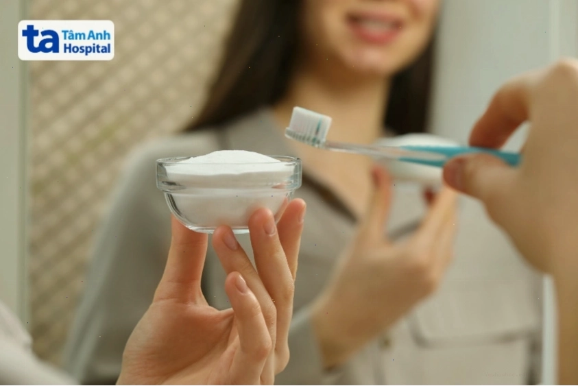 Người cầm bàn chải đánh răng và bát baking soda, chuẩn bị làm sạch răng tự nhiên.